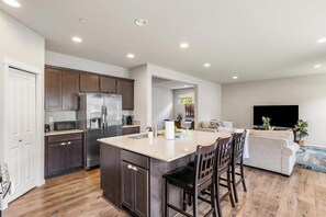A modern kitchen with a central island, dark wooden cabinets, and a stainless steel refrigerator. - Serene 4-bedroom house in Lake Stevens perfect for relaxing stays (Lake Stevens)