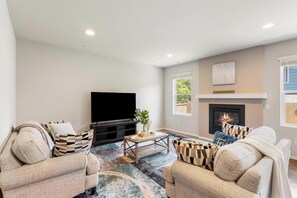 A living room with two sofas, a coffee table, a flat-screen TV, and a fireplace. - Serene 4-bedroom house in Lake Stevens perfect for relaxing stays (Lake Stevens)
