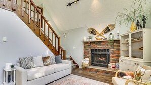 Ein Wohnzimmer mit Kamin, Treppe, Sofa und Bücherregal.