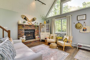 Un salon chaleureux avec une cheminée, des sièges confortables et une vue sur l’extérieur.