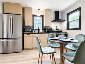 A modern kitchen with stainless steel appliances, wooden cabinets, and a dining area with a round table and chairs. - NEW Cabin Washington: Hot Tub, Firepit, BBQ (Beaver)