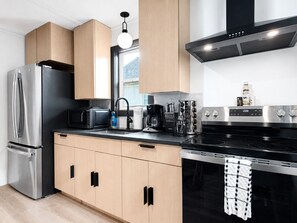 Una cocina moderna con electrodomésticos de acero inoxidable, armarios de madera y encimera negra.