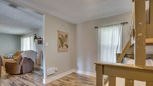 Ein Zimmer mit Holzboden, einem braunen Ledersessel, einem weißen Heizkörper und einem Fenster mit Vorhängen.