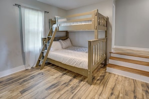 Una cama litera con escalera de madera, una cortina blanca y una escalera de madera.