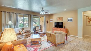 A living room with a sofa, armchair, coffee table, and a TV stand. - Pool Access! Extended Desert Escape Near St George (Washington)