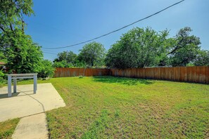 A backyard with a wooden fence, a concrete patio, and a metal table. - Central, Peaceful: 3 Mi to JBSA Lackland (San Antonio)