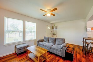 A living room with a sofa, a coffee table, a ceiling fan, and a dining area with stools. - Central, Peaceful: 3 Mi to JBSA Lackland (San Antonio)