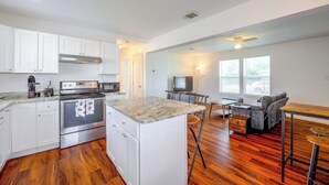 A modern kitchen with white cabinets, stainless steel appliances, and a marble countertop.