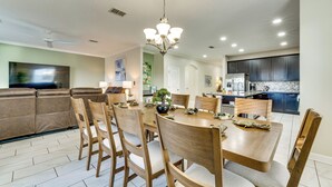 Un coin repas avec une table ronde, des chaises en bois et un lustre.