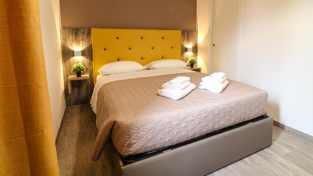 Hotellihuone, jossa on sänky, yöpöydät ja yölamppu.
