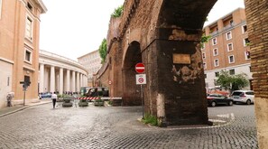 Eine Kopfsteinpflasterstraße mit einem historischen Gebäude, das einen großen Bogen und ein Schild mit der Aufschrift 'VIA DEL MASCHERINO' zeigt.