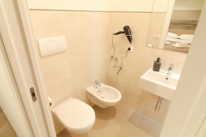 Ein Badezimmer mit Toilette, Bidet und Waschbecken mit Spiegel.