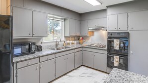 A modern kitchen with grey cabinets, a stainless steel refrigerator, a microwave, a sink, and a built-in oven. - Minutes From Chattanooga / The Scenic City (Rossville)