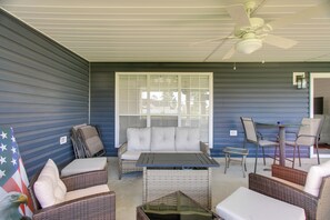 A covered patio area with wicker furniture, a ceiling fan, and a view through large windows. - Peaceful Lake Escape w/ Dock in Coffee County (Douglas)