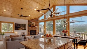 A spacious living area with a large island, wooden ceiling, and large windows offering a mountain view. - Rocky Mtn Hideaway w/ Hot Tub & Panoramic Views (Fairplay)