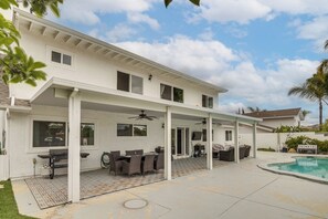 A covered patio with a pool, outdoor furniture, and a ceiling fan.