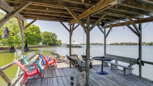 A wooden deck with chairs, a swing, and a table overlooking a body of water. - Tons of Fun at 'Camp Flamingo' on Lake Bruin! (St Joseph)