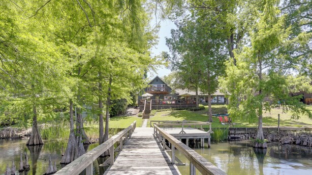 A wooden pier leading to a lodge surrounded by trees and water. - Tons of Fun at 'Camp Flamingo' on Lake Bruin! (St Joseph)