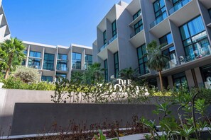 Ein modernes Hotel mit auffälliger Beschilderung, mehreren Balkonen und üppiger Bepflanzung.