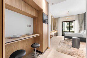 Ein modernes Hotelzimmer mit einer Holz-Kochnische, einem Bett, einem großen Fenster und minimalistischer Einrichtung.