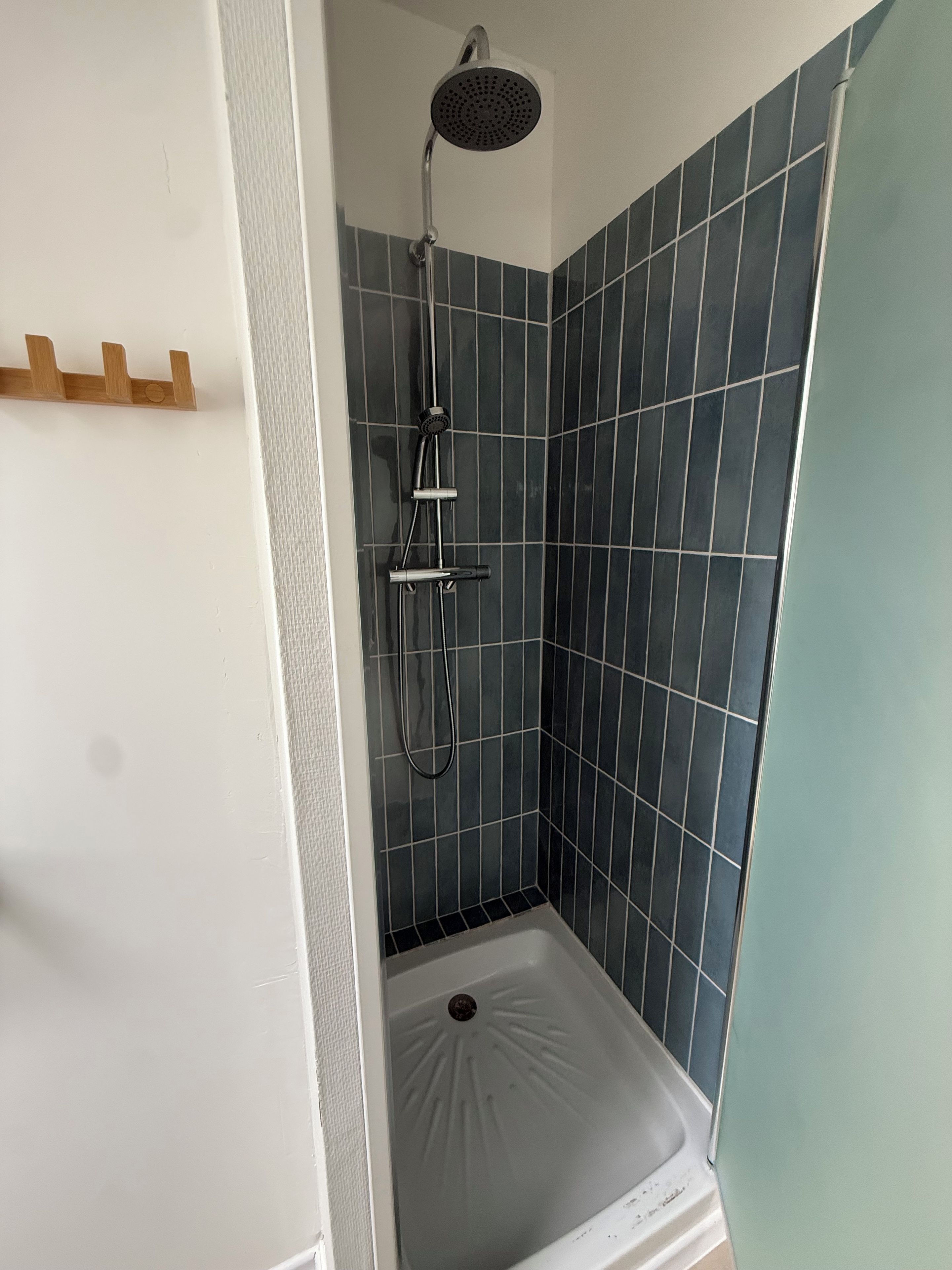 A shower with a handheld showerhead and a handheld shower attachment.