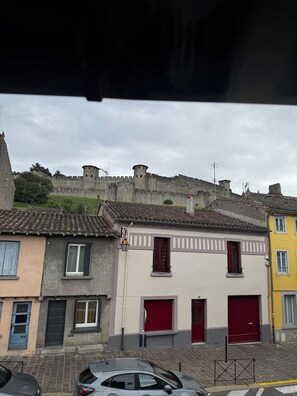 A street with buildings, a castle in the background, and a car parked in front. - Town house at the foot of the Cité de Carcassonne (Carcassonne)