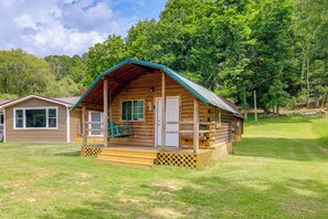 Eine Blockhütte mit Veranda, einer Haustür und einer kleinen Treppe, die hinauf führt.