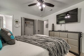 Ein Schlafzimmer mit Bett, Deckenventilator, Fernseher, Kommode und Schrank.