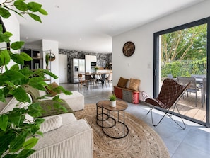 A modern living space with a dining area, kitchen, and a large sliding glass door leading to an outdoor patio. - Contemporary house with jacuzzi & outdoor space (Les Sables-d´Olonne)
