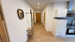 A narrow hallway leading to a kitchen with a stove, oven, and white cabinets.