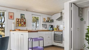 Eine moderne Küche mit weißen Schränken, einem eingebauten Backofen und einem violetten Rollwagen.