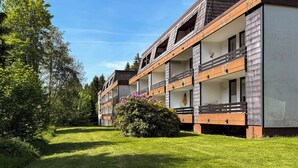 Ein mehrstöckiges Hotel mit Balkonen, einem gepflegten Rasen und umgebender Bepflanzung.
