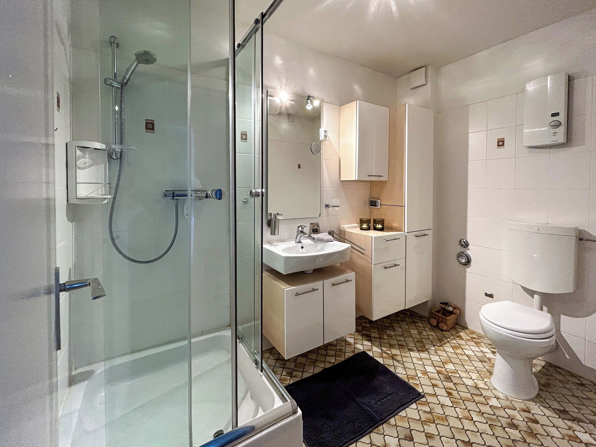 A modern bathroom with a glass-enclosed shower, a sink, and a toilet.