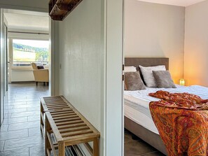 A bedroom with a bed, pillows, a bedside lamp, and a bench. - Cozy vacation apartment with a view, starting point for hikes, near Winterberg (Winterberg)
