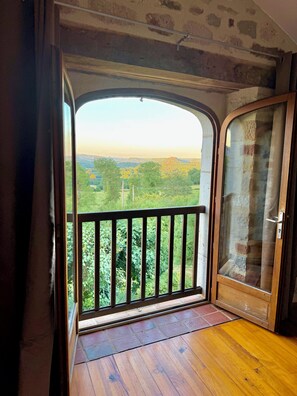 Uma porta aberta que dá para uma varanda com vista para uma paisagem verde.