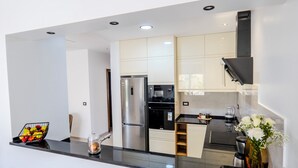 Een moderne keuken met een koelkast, oven en koffiezetapparaat.