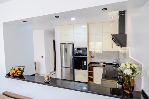 Eine moderne Küche mit Kühlschrank, Backofen und Kaffeemaschine.