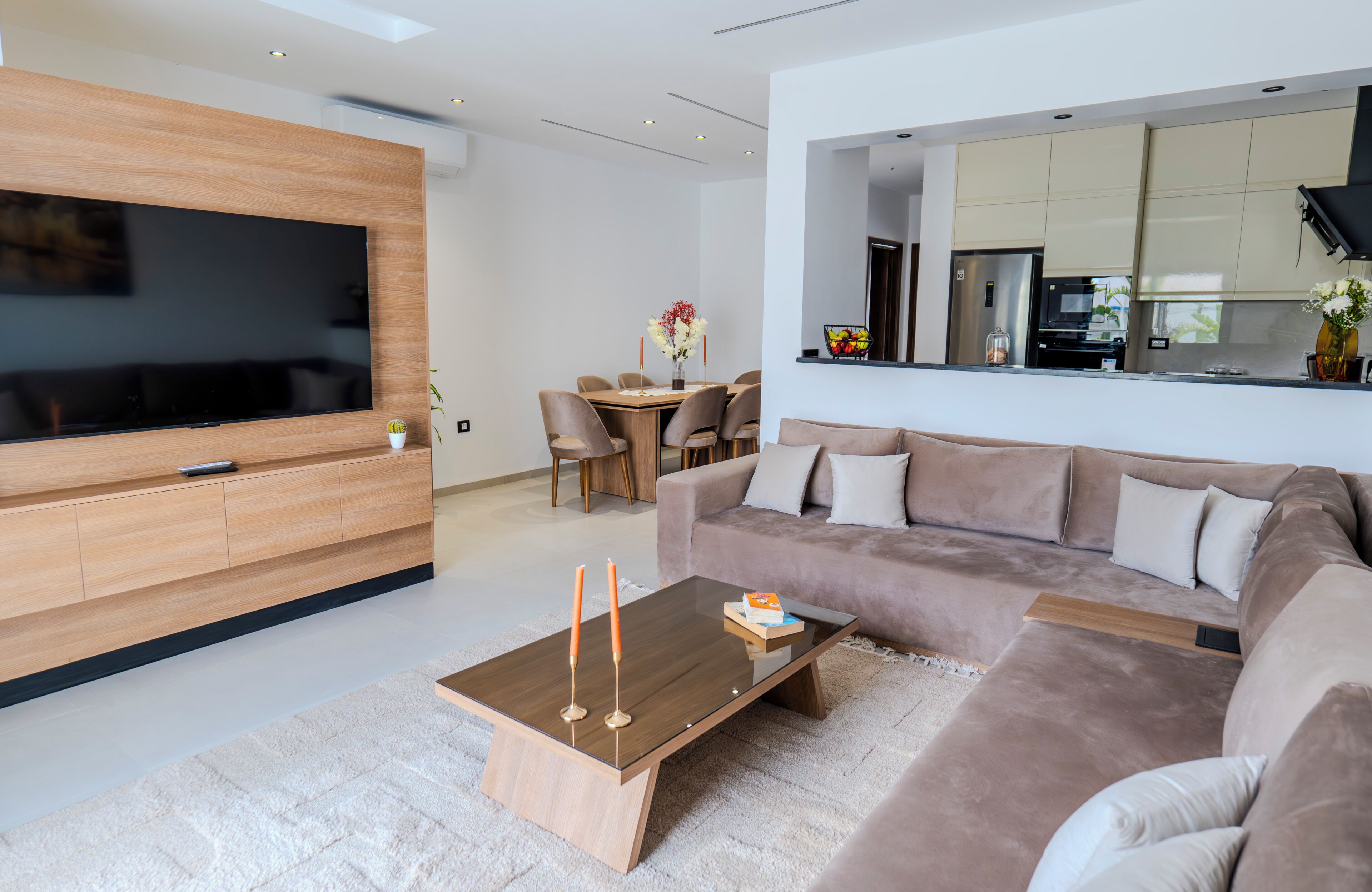 Un salon moderne doté d’un téléviseur à écran plat, d’une table basse en bois, d’un canapé et d’un coin repas avec des chaises et une table.