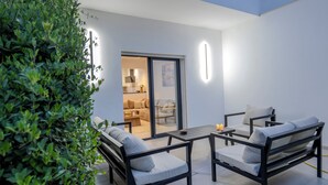 Een terras buiten met een bank, stoelen en een tafel.