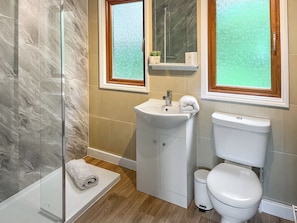 Ein Badezimmer mit Duschkabine aus Glas, einem Waschbecken mit Spiegel darüber und einer Toilette.
