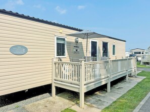 Ein Caravan mit Balkon, einem Schild mit der Aufschrift 'Rivendale Super 35 CL' und einer Plakette mit 'Meadow Lakes Caravan Hire'.