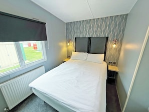 Ein Schlafzimmer mit einem Bett, einem Fenster mit Blick, einem Heizkörper und zwei Nachttischlampen.