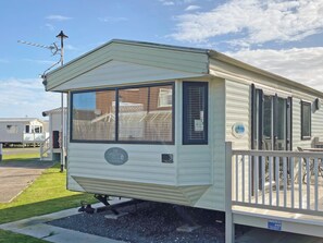 Ein Wohnmobil mit umzäunter Terrasse, Satellitenschüssel und blauem Himmel.