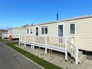 A row of mobile homes with a white deck and a small staircase leading to the entrance. - Palm Grove 2 - UKC9557 (Chapel St Leonards)
