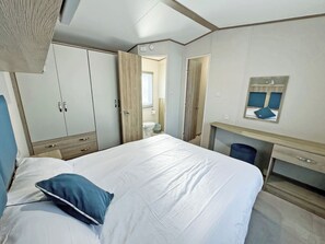 A bedroom with a bed, a wardrobe, a desk, and a mirror.