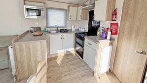 Une petite cuisine équipée d’un four à micro-ondes, d’une cuisinière, d’un évier et de placards de rangement.