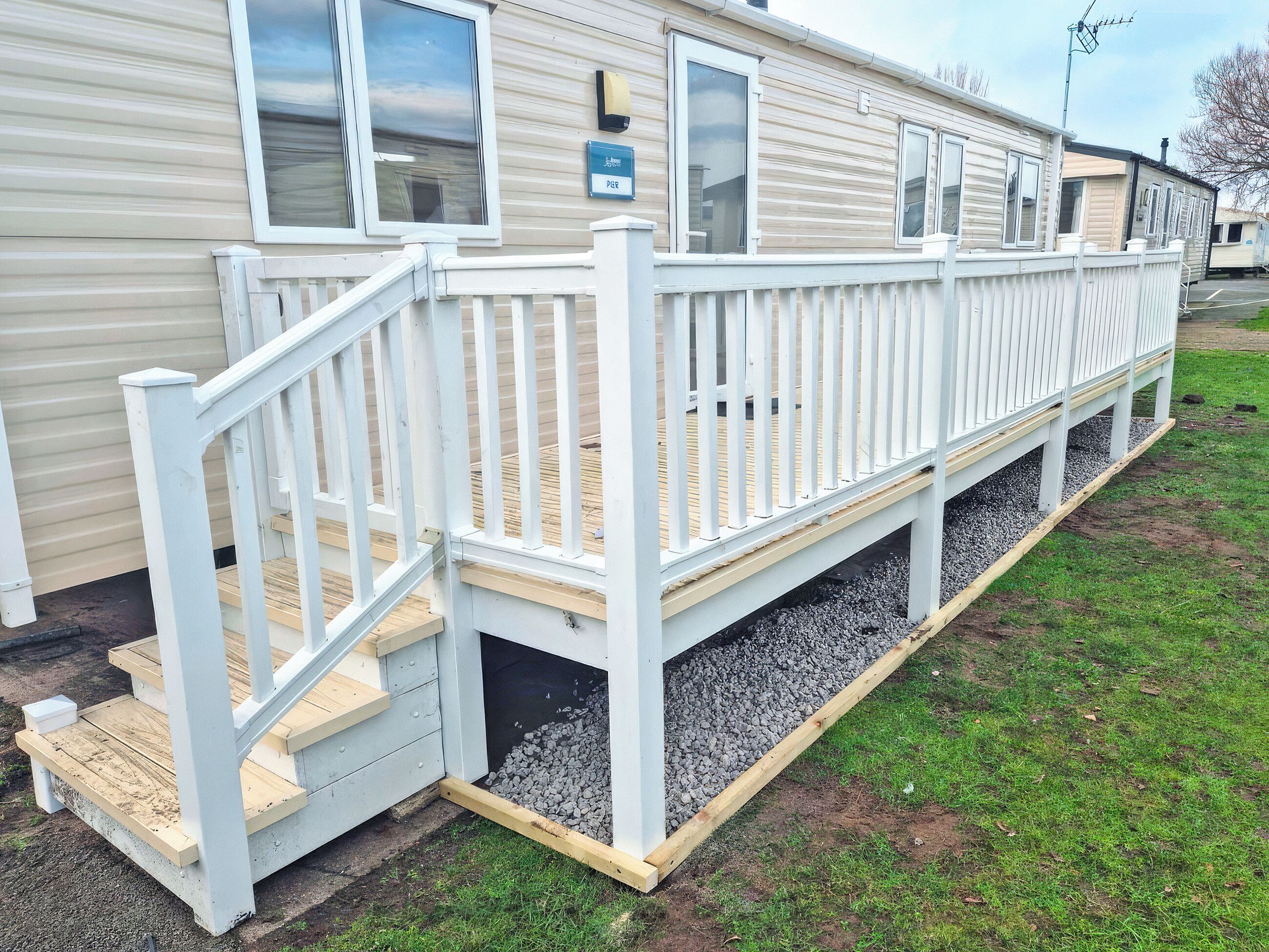 A mobile home with a white deck and a small porch area.