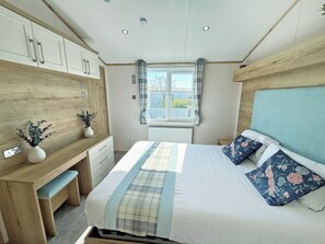Ein Schlafzimmer mit Bett, Nachttisch, Schminktisch, Fenster und Blick ins Freie.