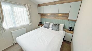 A bedroom with a bed, a nightstand, a lamp, a radiator, and a window with curtains.