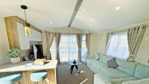 A modern living space with a kitchen area, a light green sofa, and a dining bar with stools. - Skegness Fields 108 - UKC9566 (Skegness)
